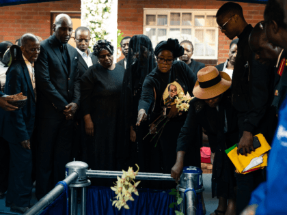 Bona Mugabe Chikore (CR), daughter of former Zimbabwe president Robert Mugabe, throws flowers ontop of her fathers coffin next to her mother Grace Mugabe (C) after the coffin of former Zimbabwe president Robert Mugabe was lowered at his home village in Kutama, on September 28, 2019. - The remains of …