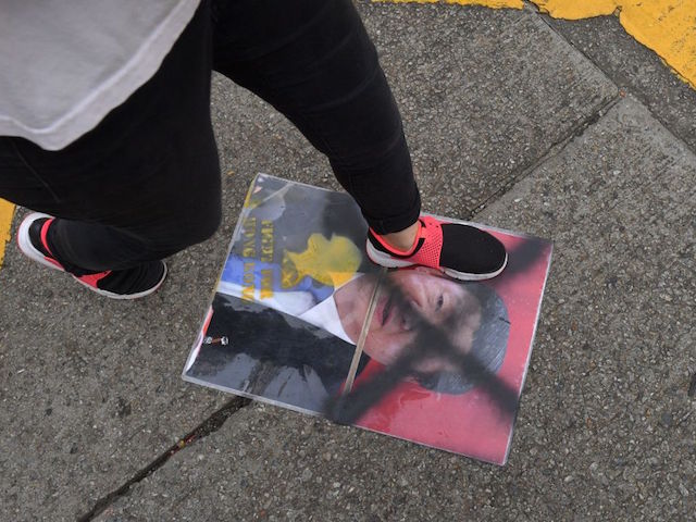 A protester steps on an image of China's President Xi Jinping during an unsanctioned march through the streets of Hong Kong on September 29, 2019, part a coordinated day of global protests aimed at casting a shadow over communist China's upcoming 70th birthday. - Hong Kong descended into a second day of clashes between pro-democracy protesters and riot police on September 29 as activists step up their nearly four months campaign ahead of the 70th anniversary of communist China's founding. (Photo by Nicolas ASFOURI / AFP) (Photo credit should read NICOLAS ASFOURI/AFP/Getty Images)