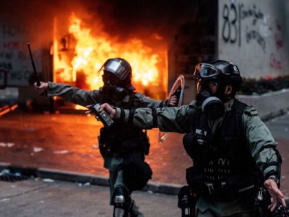 TOPSHOT - Police stand in front of a fire at the entrance to a building after clashes in t