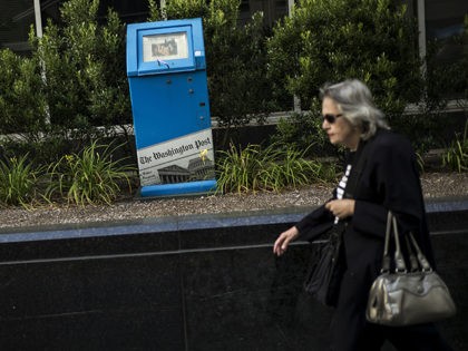 A woman walks past a Washington Post newspaper box outside the Washington Post on August 5