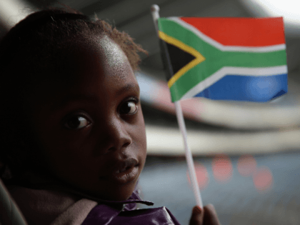 A girl waves a South African flag while watching the official memorial service for Nelson