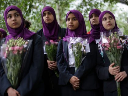 TOPSHOT - Pupils from Eden Girls' School in Walthamstow holds flowers at Potters Fields Park in London on June 5, 2017, during a vigil to commemorate the victims of the terror attack on London Bridge and at Borough Market that killed seven people on June 3. London police made a …