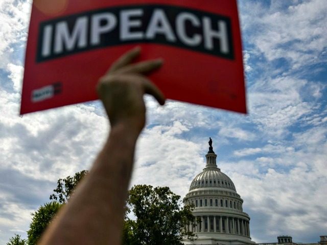 A protester holds up a sign in favor of impeachment outside the U.S. Capitol building on T