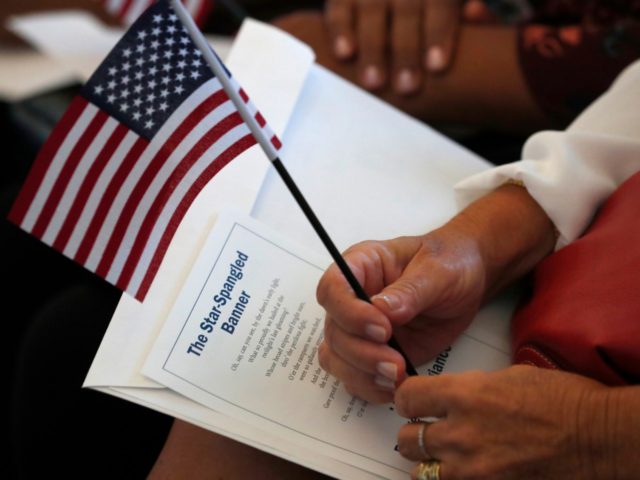 FILE - In this Aug. 16, 2019, file photo a citizen candidate holds an American flag and the words to The Star-Spangled Banner before the start of a naturalization ceremony at the U.S. Citizenship and Immigration Services Miami field office in Miami. U.S. Citizenship and Immigration Services officers can now …