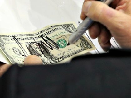 Donald Trump signs a dollar bill for a supporter during a campaign rally in Richmond, Va.,