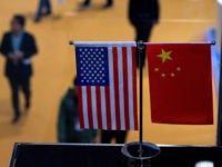 This picture taken on November 6, 2018 shows a Chinese and US flag at a booth during the first China International Import Expo (CIIE) in Shanghai. - There is a notable absentee among the dozens of national pavilions at a massive Chinese import fair -- the United States -- a …
