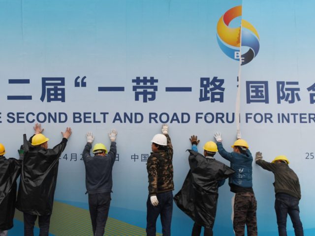 Workers take down a Belt and Road Forum panel outside the venue of the forum in Beijing on