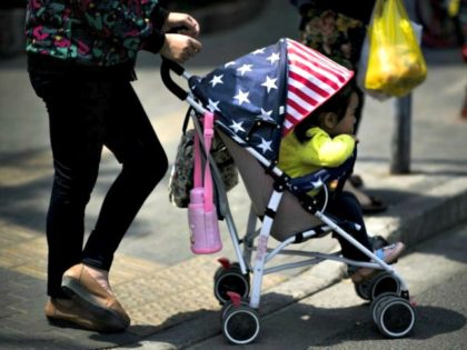 File picture of a woman pushing a child in a stroller, adorned with colours of the US national flag, along a street in Shanghai (AFP Photo/Johannes EISELE)