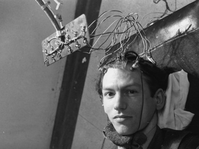 A patient is connected to an encephalogram machine, which will record his brain's activity by reading the rhythmic electric pulses it emits. This takes place in the laboratory of Dr Grey Walter at the Burden Neurological Institute at Bristol University. Original Publication: Picture Post - 4998 - New Light On …