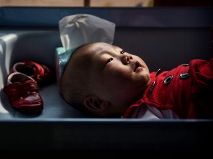 BEIJING, CHINA - APRIL 02: A young orphaned Chinese girl lays on a changing table at a foster care center on April 2, 2014 in Beijing, China. China's orphanages and foster homes used to be filled with healthy girls, reflecting the country's one-child policy and its preference for sons. Now …
