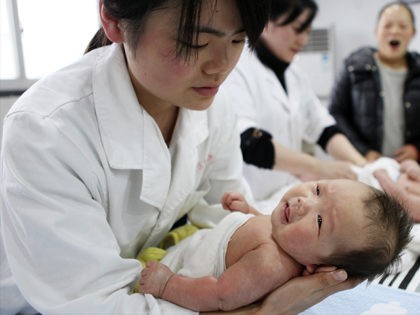 This photograph taken on December 15, 2016, shows a nurse holding a baby at an infant care centre in Yongquan, in Chongqing municipality, in southwest China. China had one million more births in 2016 than in 2015, following the end of the one-child policy at the end of 2015. / …