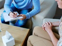 Male psychologist making notes during psychological therapy