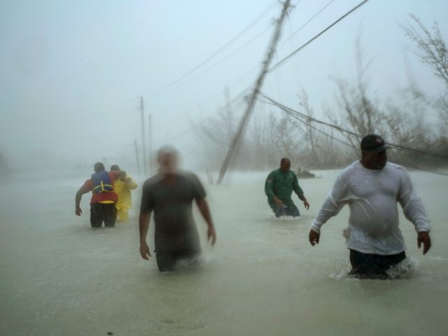 Volunteers walk under the wind and rain from Hurricane Dorian through a flooded road as th