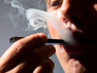 An illustration shows a man exhaling smoke from an electronic cigarette in Washington, DC on October 2, 2018. - In just three years, the electronic cigarette manufacturer Juul has swallowed the American market with its vaporettes in the shape of a USB key. Its success represents a public health dilemma …