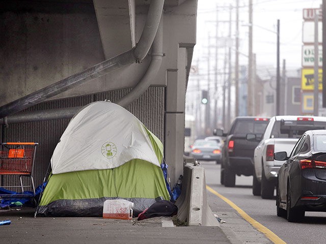 A tent sits under an on-ramp as traffic drives past during morning rush hour in Seattle on