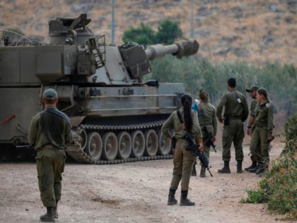 Israeli soldiers stand next to a self-propelled artillery gun near the Lebanese border out