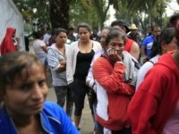 Women and men stand in separate lines to sort through donated clothing at a sports complex sheltering various migrant caravans trying to reach the U.S. border, in Mexico City, Tuesday, Nov. 13, 2018. While thousands in one caravan continued moving north through Nayarit state on Tuesday, over 1,000 migrants from …