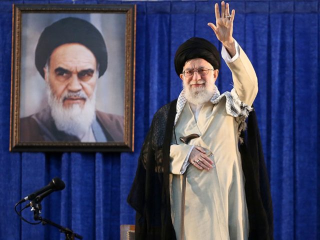 In this picture released by the official website of the office of the Iranian supreme leader, Supreme Leader Ayatollah Ali Khamenei waves to the crowd while attending a ceremony marking 30th death anniversary of the late revolutionary founder Ayatollah Khomeini, shown in the poster at rear, at his mausoleum just …