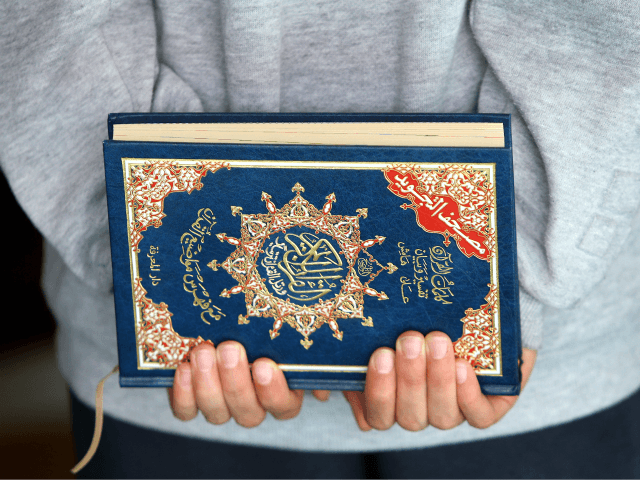 A young boy holds the Quran in his hands during …