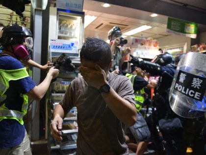 A man covers his face as riot police use pepper spray during clashes with pro-democracy protesters in Yeun Long district in Hong Kong on September 21, 2019. - Riot police and protesters fought brief skirmishes in a town close to the Chinese border on September 21, the latest clashes during …
