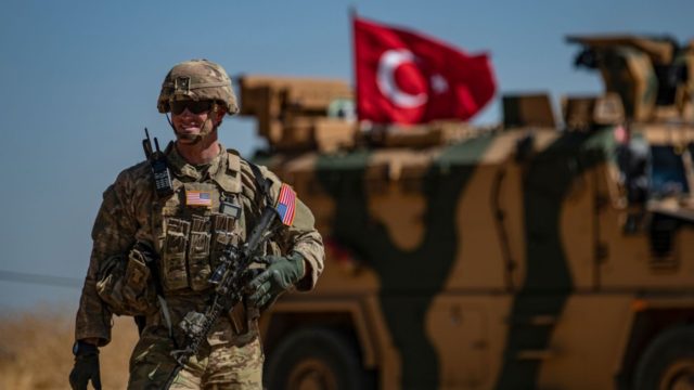An American soldier stands guard during a joint patrol with Turkish troops in the Syrian v