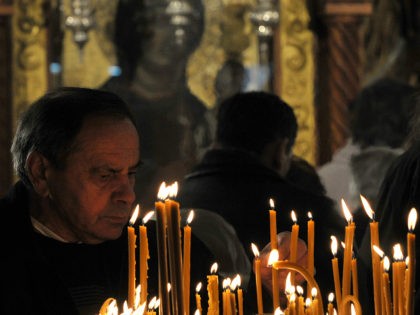 A Bosnian Orthodox Christian man lights a candle as she attends a Christmas morning religi
