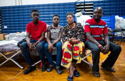 Nathalie Muenda, Kashala Kalombo and their two sons, migrants from Congo sit on their cot at The Expo, a sports complex converted into an emergency shelter, on June 25, 2019 in Portland, Maine. - Converging from far flung corners of the earth, and operating by word of mouth and social …