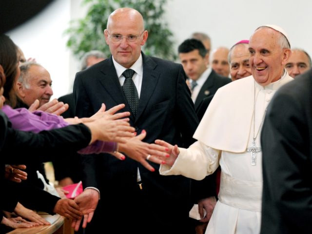 Pope Francis (R), flanked by Vatican security chief Domenico Giani (C), is welcomed by fai