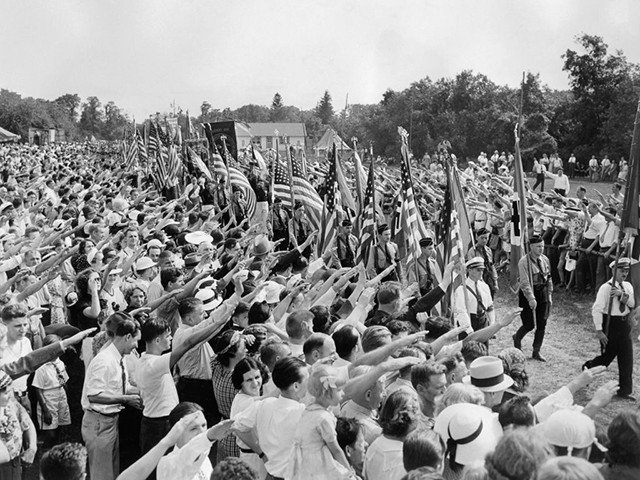 Hundreds of thousands of German-Americans sympathize with the Nazi Hitler Germany raises their hands in a Nazi salute to the passage of the German-American Bund with the German swastika flag and american flag during an annual "German Day" celebrated at Camp Siegfried in Yaphank on August 29, 1937 in Long Island, United States. (Photo by - / ACME / AFP) (Photo credit should read -/AFP/Getty Images)