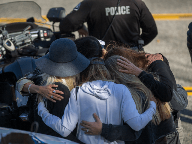 People hug and pray before the procession carrying the body of Ventura County Sheriff Sgt.