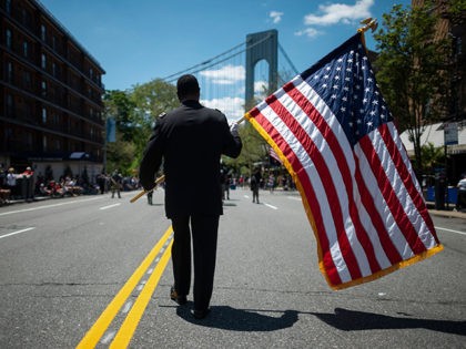 A veteran carries an American flag as he marches on the street May 27, 2019 during the 152