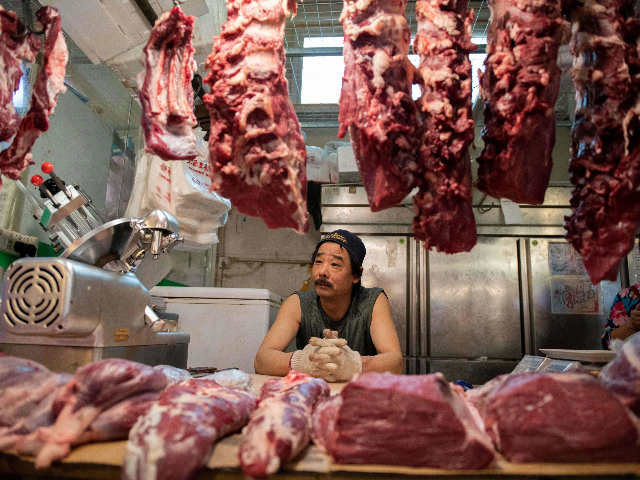 A butcher waits for customers at his stall at a market in Beijing on July 10, 2019. - Factory prices in China were unchanged in June from a year ago, data showed on July 10, reviving the prospect of deflation as the US trade war hits the crucial manufacturing sector. …
