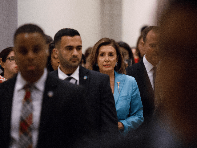 House Speaker Nancy Pelosi (D-CA) walks through a hallway amongst staff members, security,