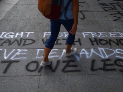 HONG KONG-CHINA-POLITICS-CRIME-UNREST A student walks past graffiti spray-painted on the pavement at the Chinese University of Hong Kong (CUHK) in Hong Kong on October 3, 2019. - Anger continued to mount over the police shooting of a teenage protester on October 1 who attacked officers, in a dramatic escalation of the violent …