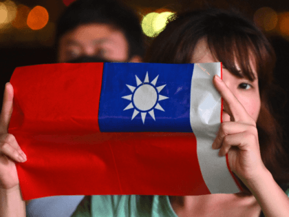 A woman holds a Taiwanese flag as she joins others at a rally to mark Taiwan's National Da