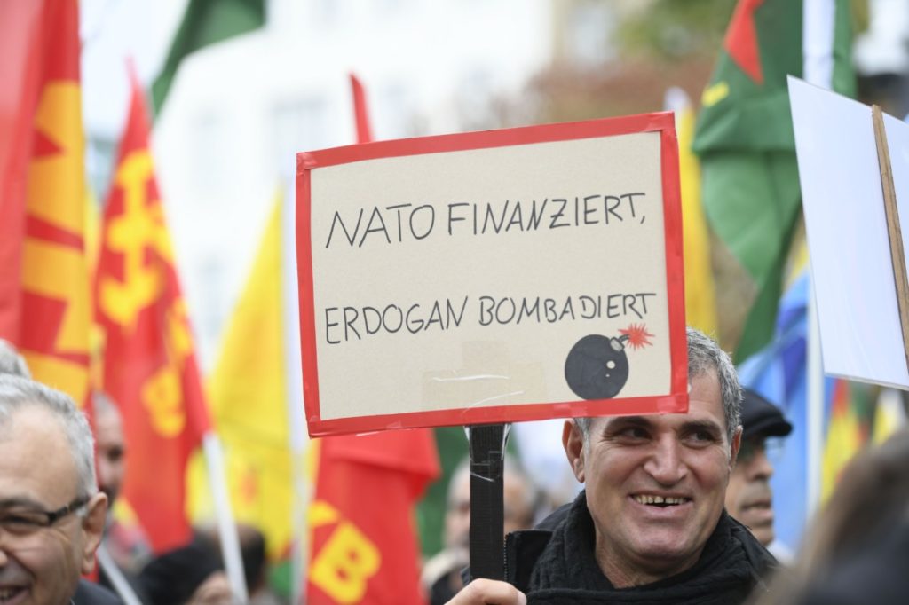 A protester holds a placard reading "NATO finances, Erdogan bombards", during a pro-Kurdish demonstration in Cologne, western Germany on October 19, 2019. (Photo by Ina Fassbender / AFP) (Photo by INA FASSBENDER/AFP via Getty Images)