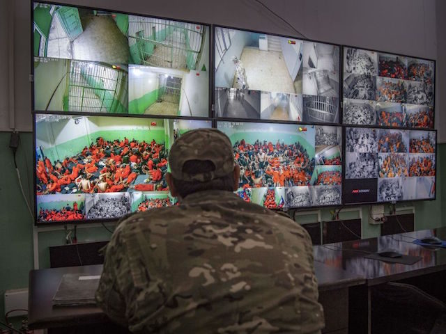 A fighter with the Syrian Democratic Forces (SDF) monitors on Surveillance screens, prisoners who are accused of being affiliated with the Islamic State (IS) group, at a prison in the northeastern Syrian city of Hasakeh on October 26, 2019. - Kurdish sources say around 12,000 IS fighters including Syrians, Iraqis …