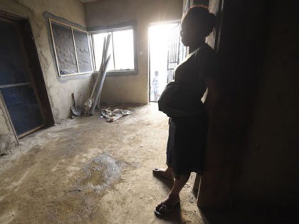 A pregnant Cameroonian refugee lean on the wall in a house, where hundreds are being shelt