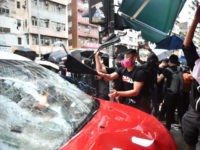 TOPSHOT - Protesters smash a taxi after the driver drove onto the pavement hitting two protesters along Cheung Sha Wan Road during a demonstration in Hong Kong on October 6, 2019. - A Hong Kong judge on October 6 rejected a challenge to an emergency law criminalising protesters wearing face …