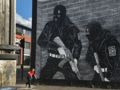 BELFAST, NORTHERN IRELAND - OCTOBER 13: A young boy runs past a loyalist paramilitary mural on the day that the new Loyalist Community Council was launched at the Park Avenue Hotel on October 13, 2015 in Belfast, Northern Ireland. The council has the backing of the three main loyalist paramilitary …
