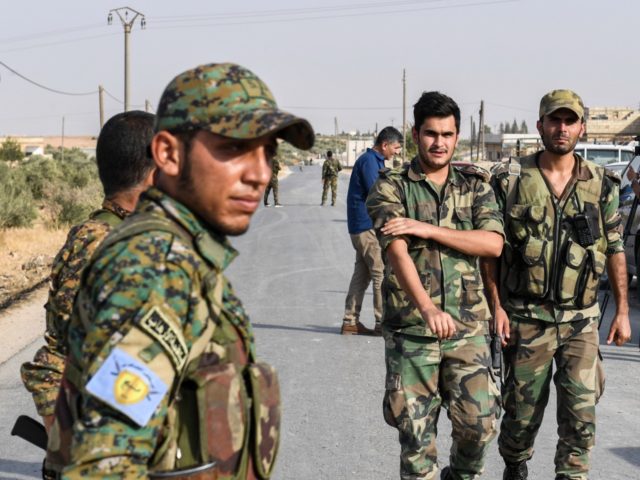 A fighter (L) wearing a military uniform bearing the insignia of the Manbij Military Counc