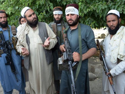 Afghan Taliban militants stand with residents as they took to the street to celebrate ceas