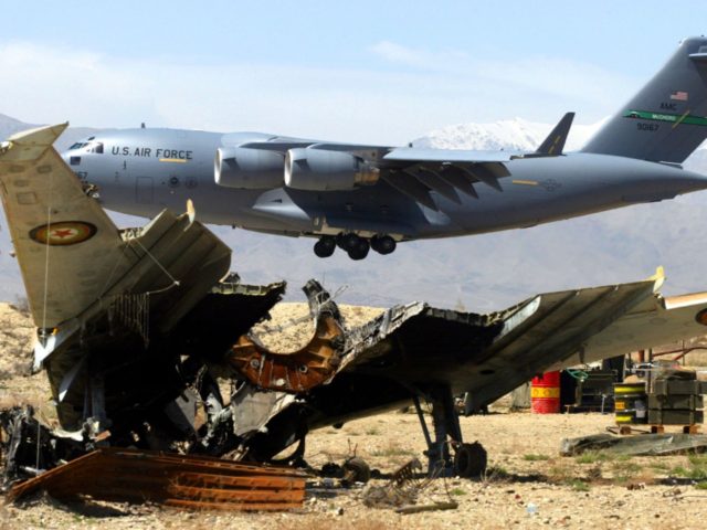 403593 08: A U.S. Air Force C-17 flies past a hulk of an old fighter jet April 9, 2002 as it prepares to land at the Bagram Air Base in Afghanistan. The Air Force continues to fly people and supplies into and out of the air base as Operation Enduring …