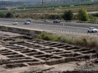 Cars drive Sunday on a highway past part of a vast 5,000-year-old cosmopolitan and planned city, one of the first and largest of the ancient Near East, excavated by the Israeli Antiquities Authority in En Esur, Israel. The archaeological site, located near Wadi Ara, was discovered before the construction of …