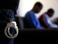 A Kurdish security officer, foreground, stands guard next to Alexanda Amon Kotey, center, and El Shafee Elsheikh, right, two British alleged members of an Islamic State cell dubbed "The Beatles," known for beheading hostages in northern Syria, during an interview with The Associated Press, at a security center, in Kobani, …