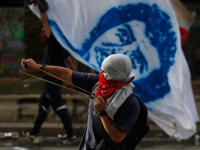 SANTIAGO, CHILE - OCTOBER 22: A demonstrator clashes with riot police during the fifth day