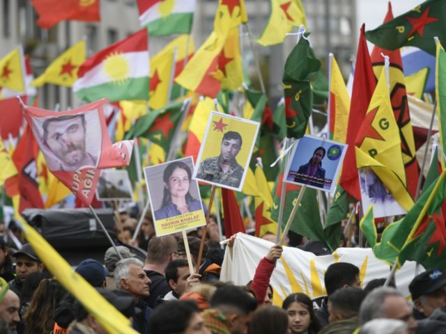 Kurdish protesters wave their national flags and hold photos of Kurdish political leader k