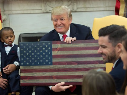WASHINGTON, DC - DECEMBER 05: (AFP OUT) U.S. President Donald Trump holds a plaque made by Brian Steorts the owner of Flags of Valor during a meeting with Steorts and other business owners and their families to discussing tax reform in the Oval Office of the White House on December …
