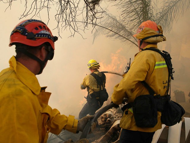 Firefighters make a stand as a wildfire approaches the backyard of a home Thursday, Oct. 2