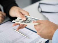Woman taking batch of hundred dollar bills. Hands close up
